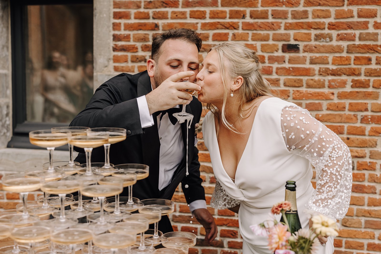 Bruidspaar drinkt samen uit een glas van de champagnetoren