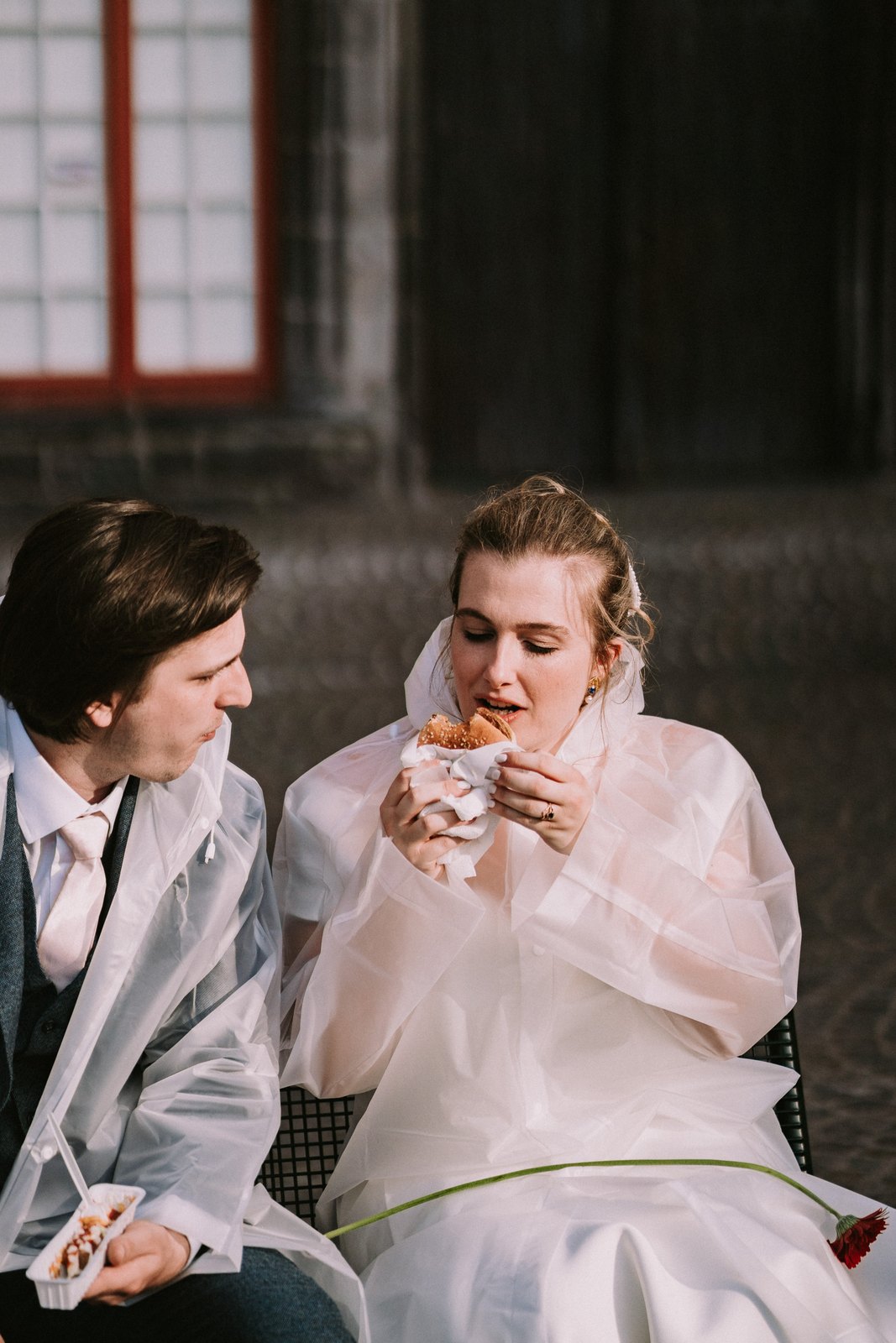 Clarissa en Sam eten een broodje in regenponcho's op hun trouwdag