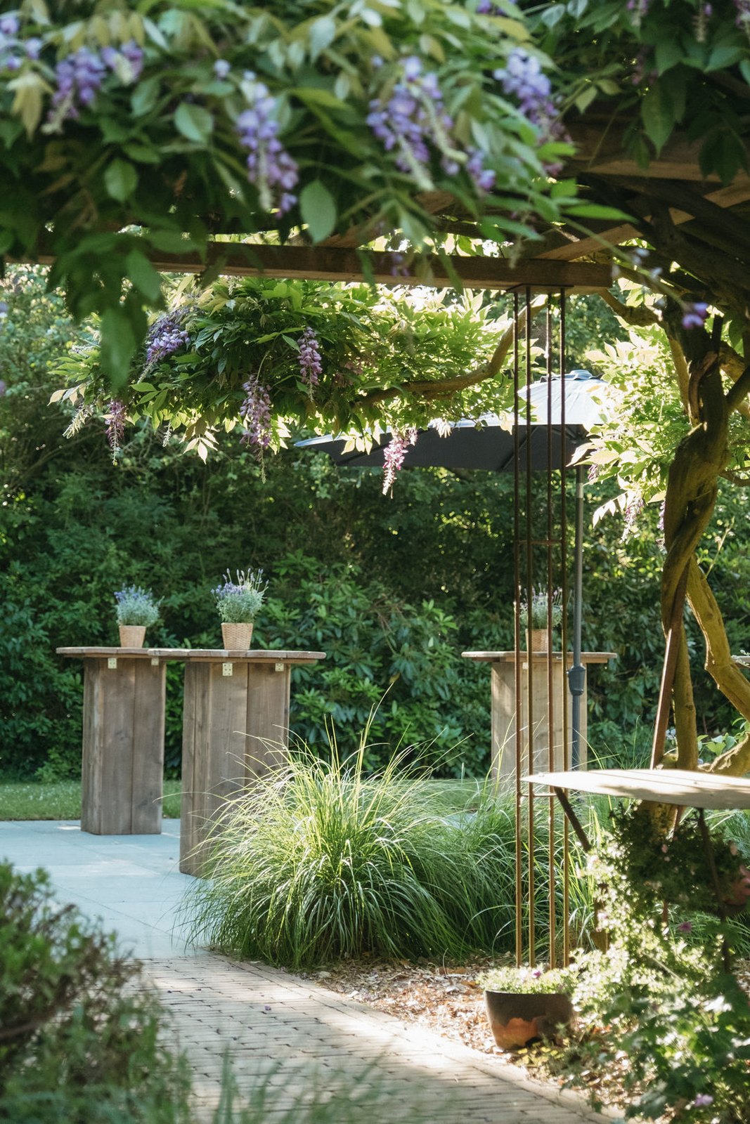 Statafels onder een blauweregenpergola op domein Côté Charme