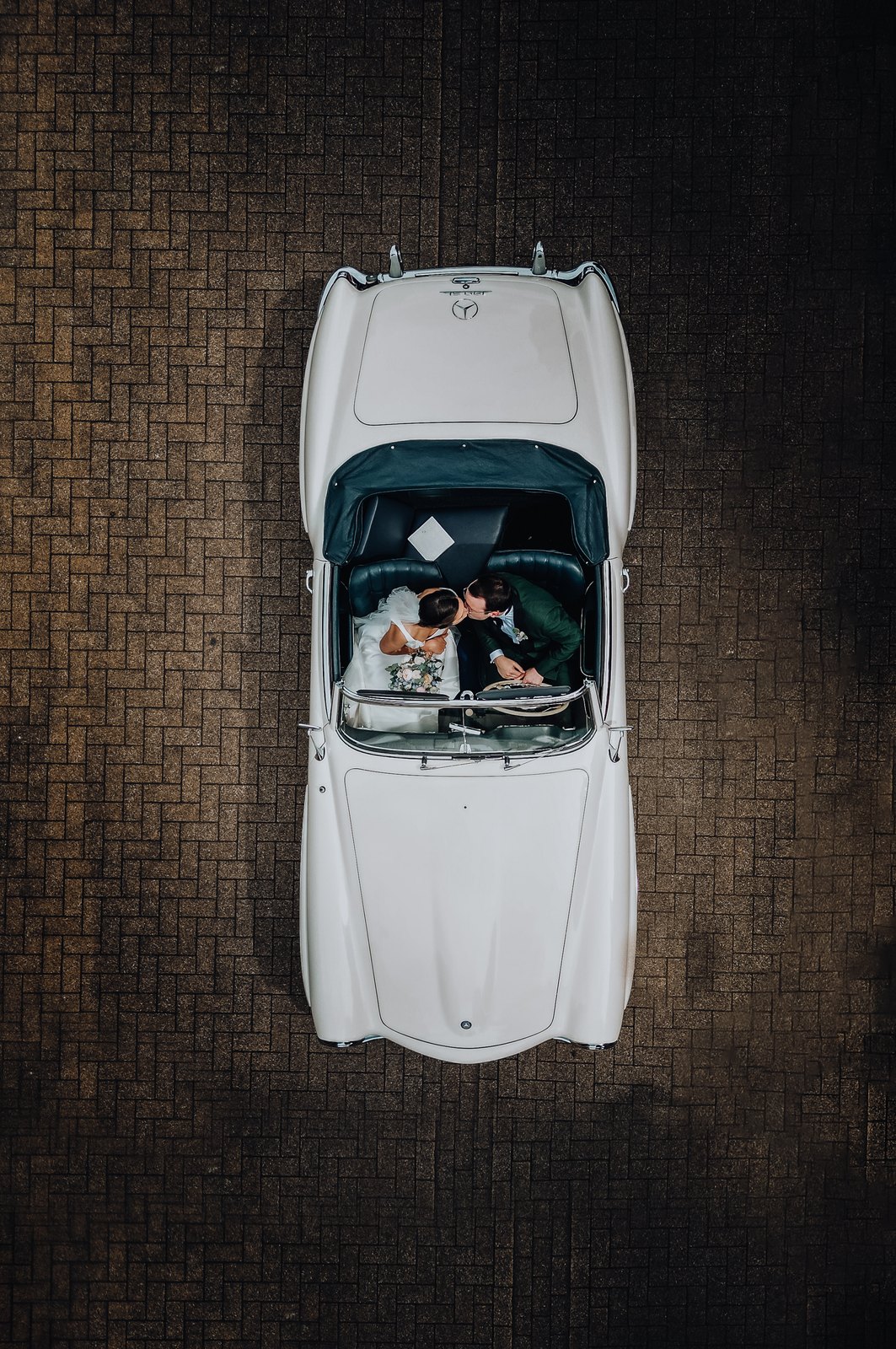 Koppel kust elkaar in een witte oldtimer, gefotografeerd van bovenaf