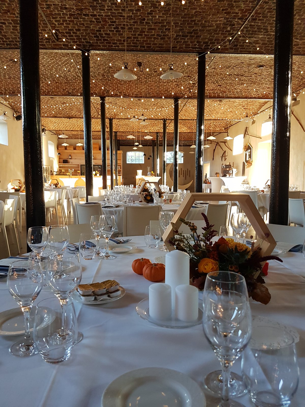 Feesttafel in de schuur met herfstbloemen, pompoenen en lichtjes