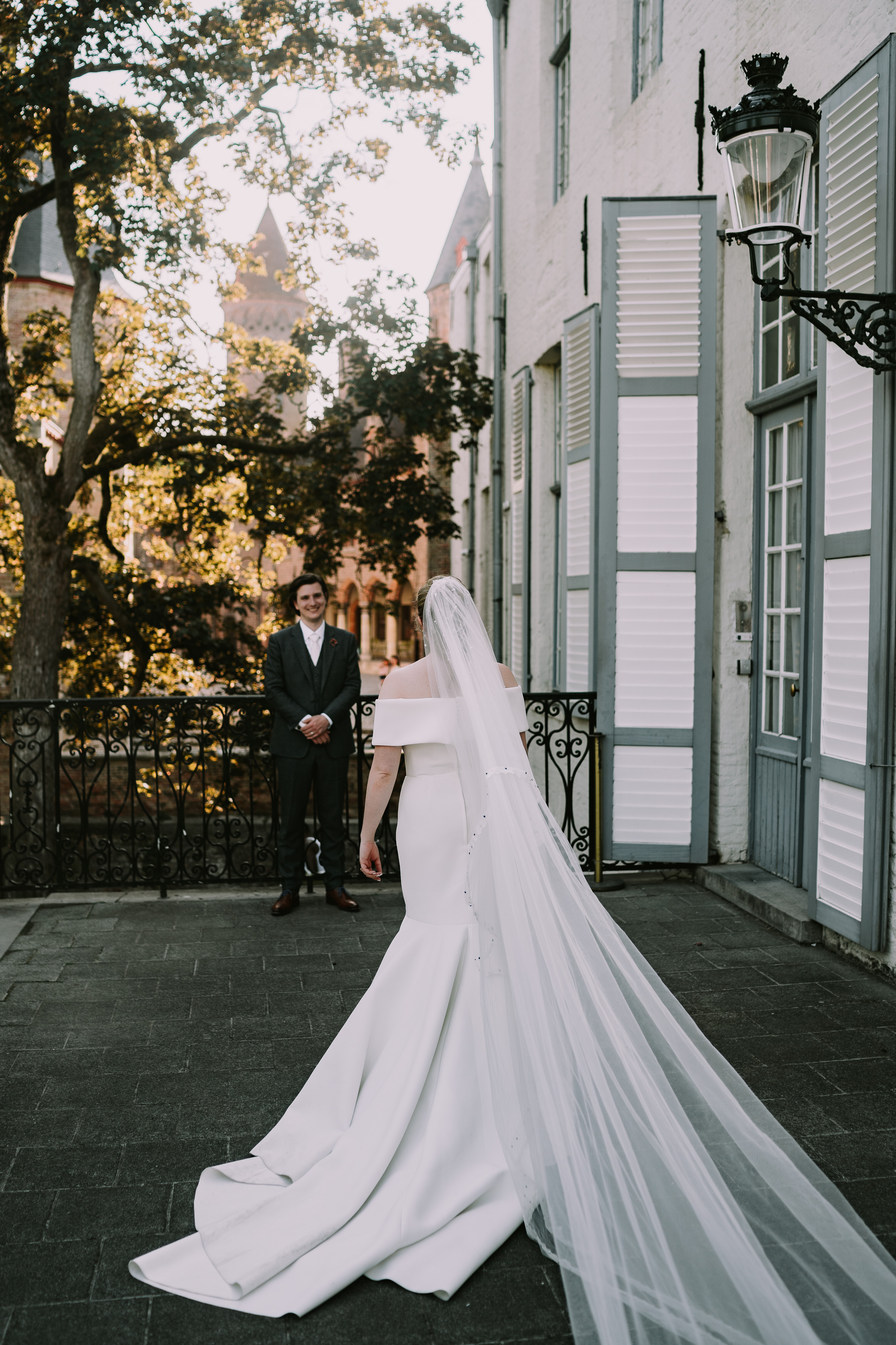 Een foto van de fotoshoot met het koppel Sam en Clarissa. Ze poseren voor een historisch gebouw in Brugge.