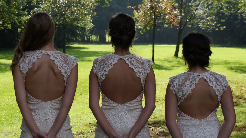 Jolien, Maureen en Lauren zijn 3 zussen die geposeerd staan met hun rug naar de camera op het trouwfeest van hun ouders. 