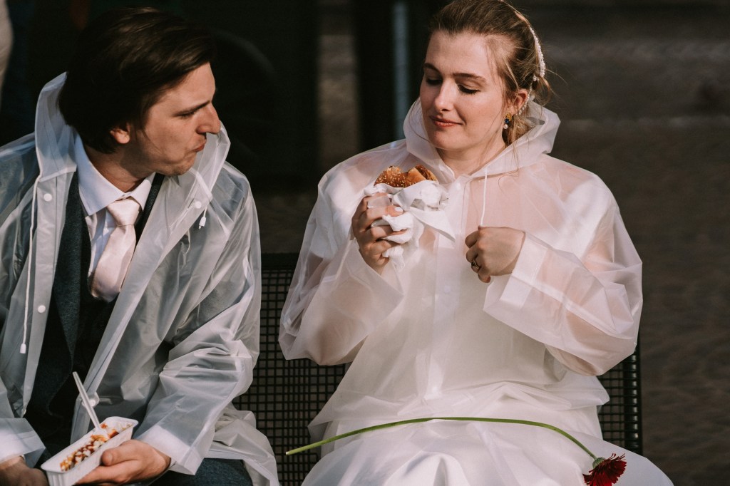 Een atypische foto van een koppel dat een hamburger eet op hun trouwdag.