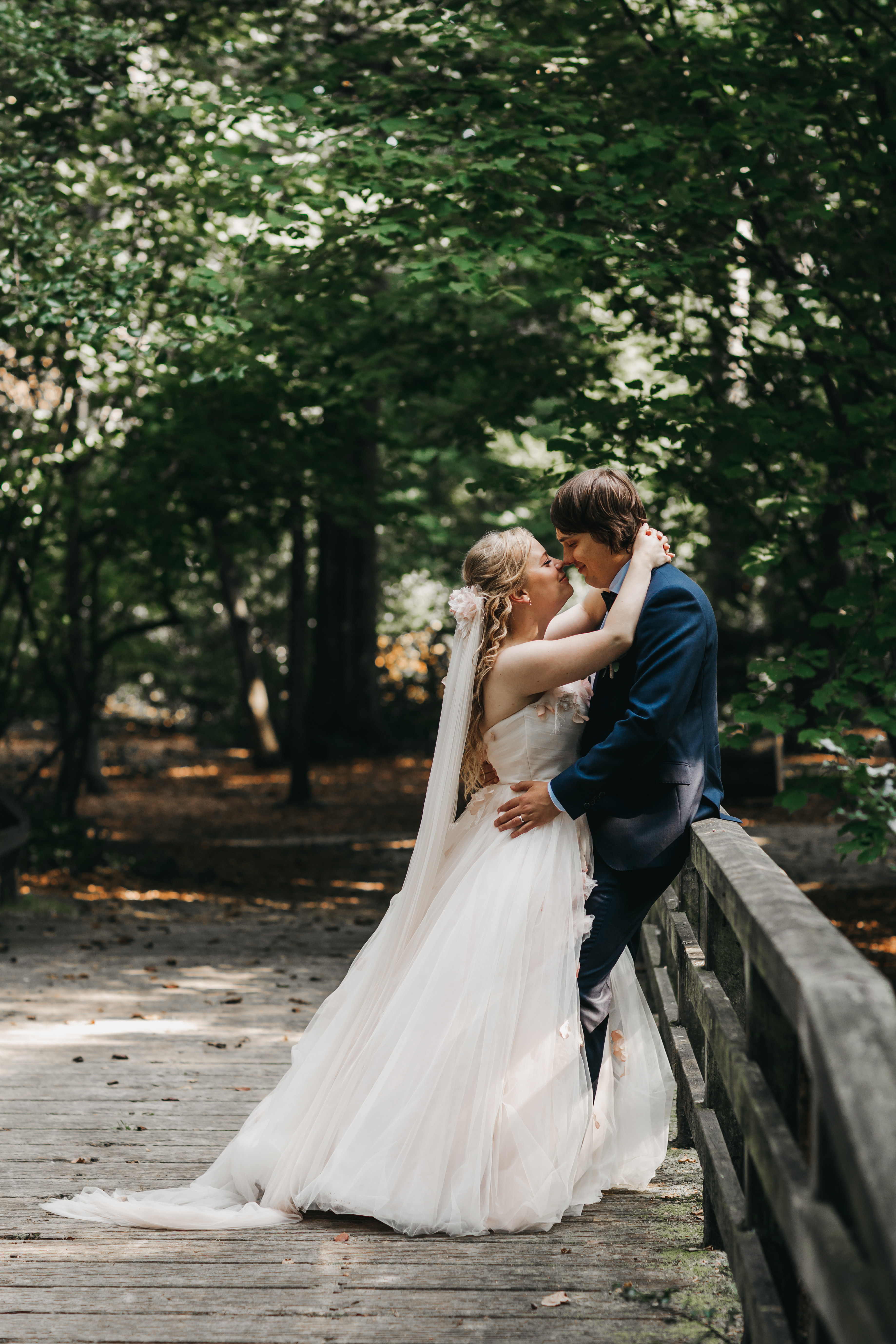 Een foto van de fotoshoot met het koppel Marijke en Robbert. Ze poseren op een idyllische brug in een bos.