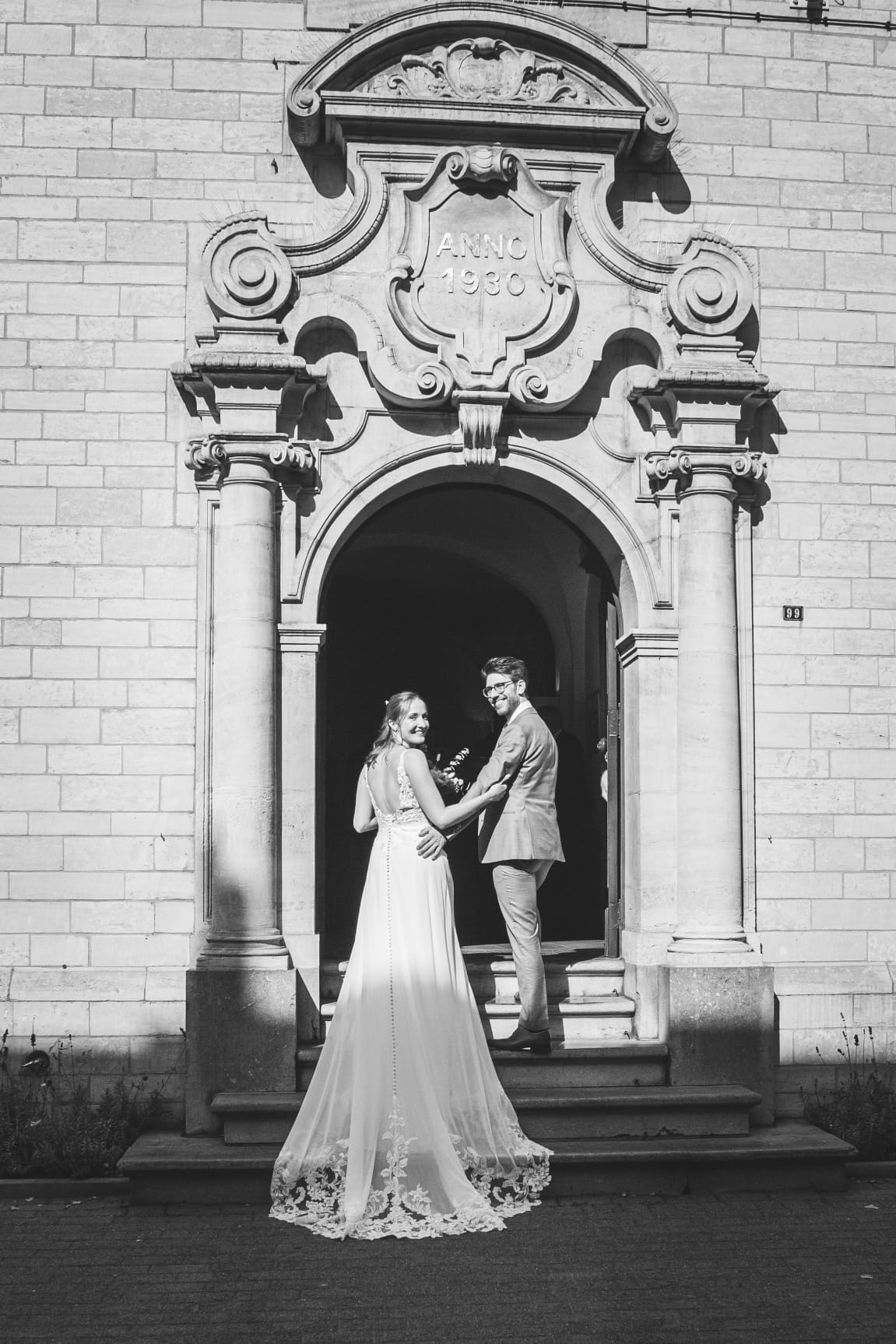 Een foto van de fotoshoot met het koppel Wouter en Laila. Ze wandelen het gemeentehuis binnen.